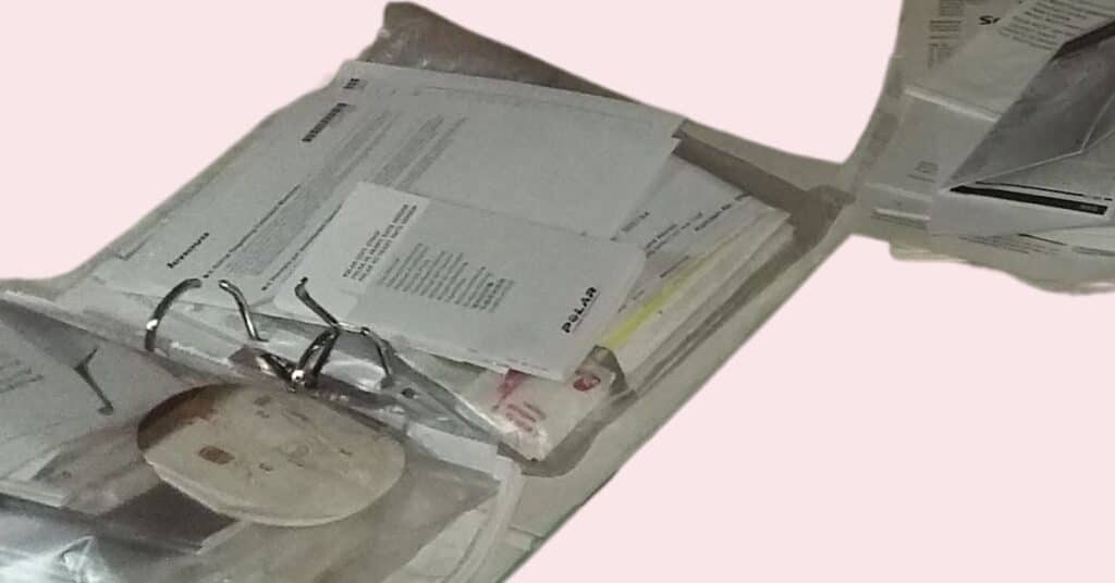 Ein Stapel Dokumente und Umschläge liegt verstreut auf einer Oberfläche, einige davon in einem Ringbuch.