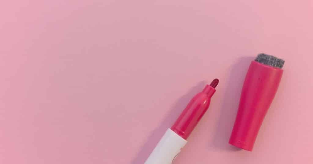 Ein rosa-weißer Marker ohne Kappe auf rosa Hintergrund.