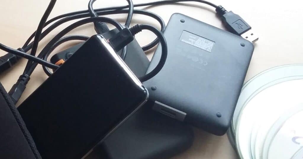Ein Durcheinander elektronischer Geräte mit Kabeln, einer Festplatte und einem USB-Anschluss auf einem Schreibtisch.