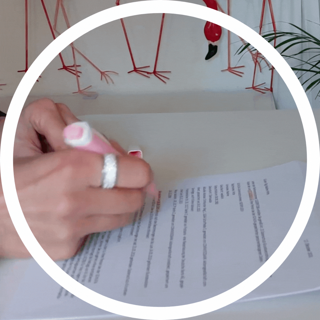 Eine Person mit einem rosafarbenen Textmarker markiert Text auf einem gedruckten Dokument an einem Schreibtisch, wobei im Hintergrund Flamingo-Illustrationen zu sehen sind.